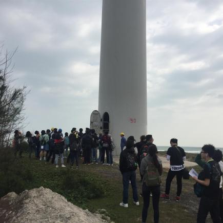 學生在參觀華能風電廠的風力發電機。